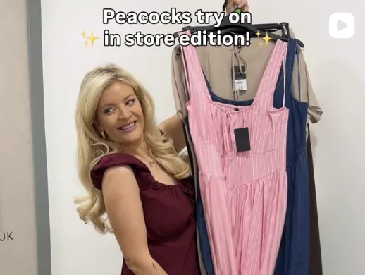 Hannah holding a pink dress on a hanger in store